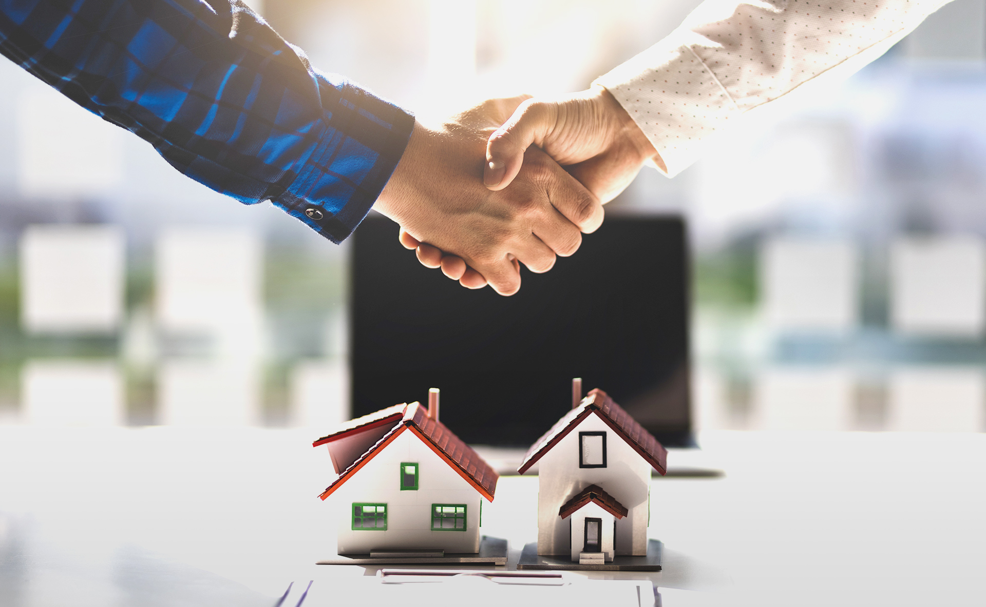 家の模型の前で握手をしている