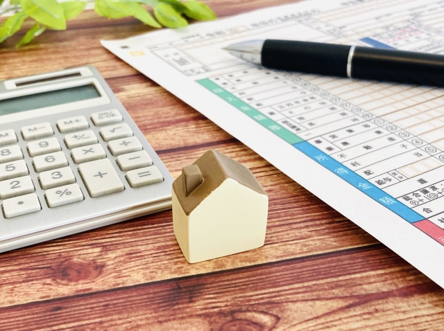 確定申告書とペンと家の模型と電卓がある