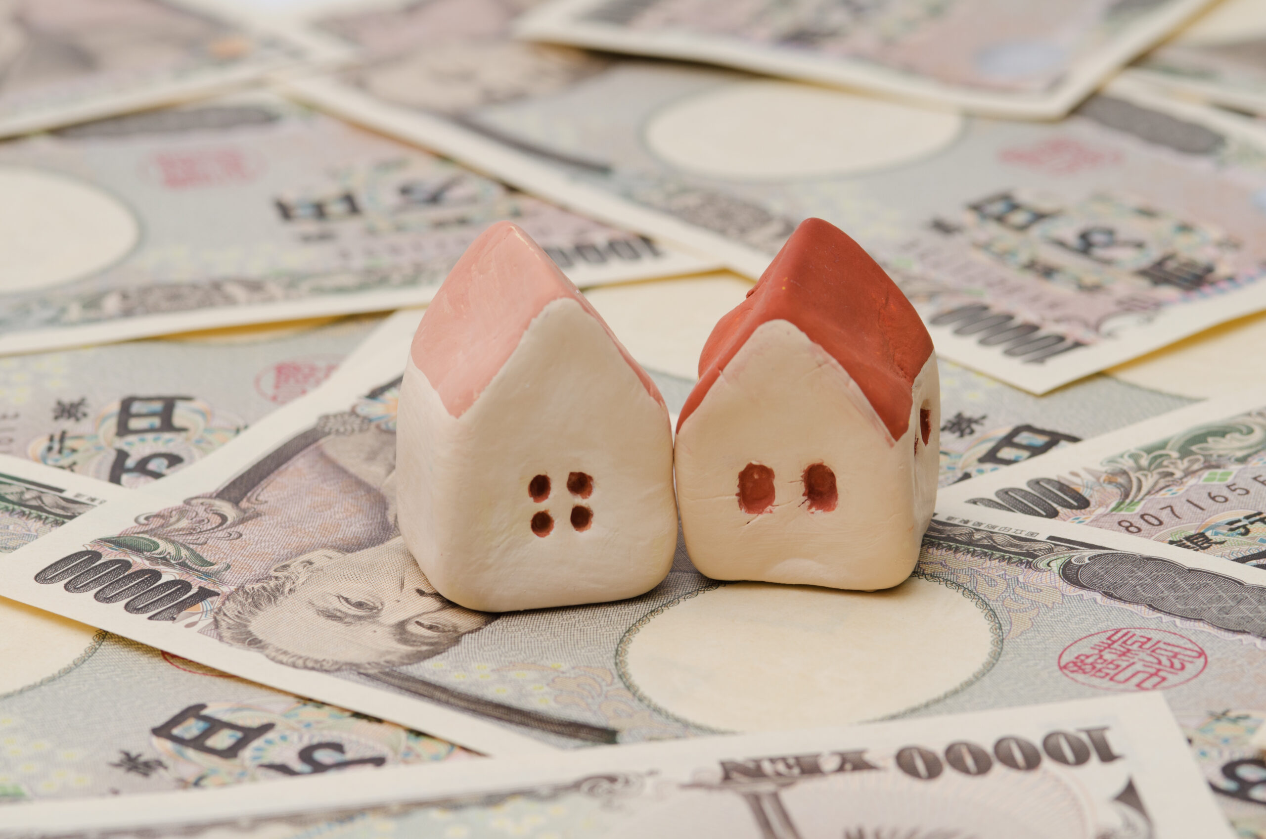 お金の上に家の模型が２つある