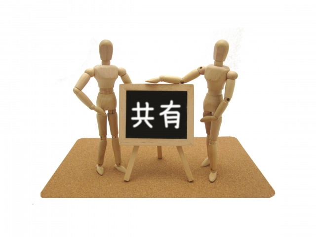 人形が共有と書いたボードを掲げている