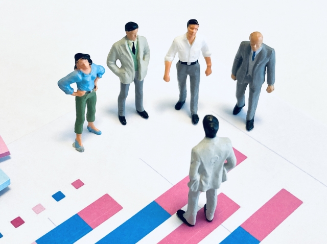 棒グラフの上で5体の人形が話しをしている