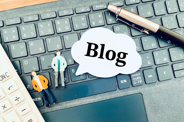 パソコンの上にBlogという文字の吹き出しと人形2体とペンがある