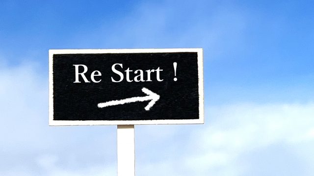 青空の前にRESTART!という文字がある看板がある