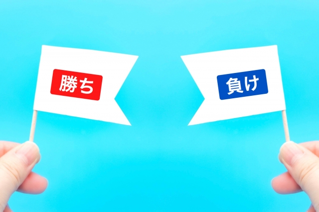 勝ちと負けという文字が書いた旗をもっている