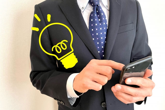 スーツをきた男が電卓をたたいている横に豆電球の絵がある