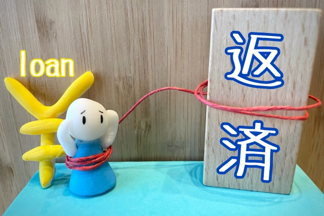 返済という文字が書かれている木と人形のおなかの部分に紐がまかれていてつながっている。人形の後ろにはloanという文字がかかれている。