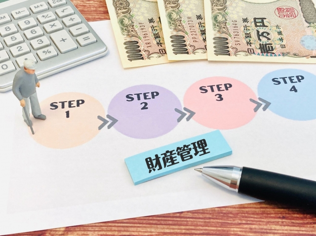電卓とペンとお金と老人の人形と財産管理やSTEP1、STEP2、STEP3、STEP4と書かれた付箋がある